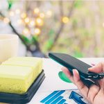 Zbliżenie osoby trzymającej telefon komórkowy na stole