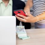 Środkowa sekcja kobiety pokazującej smartfon biznesmenowi za pomocą laptopa