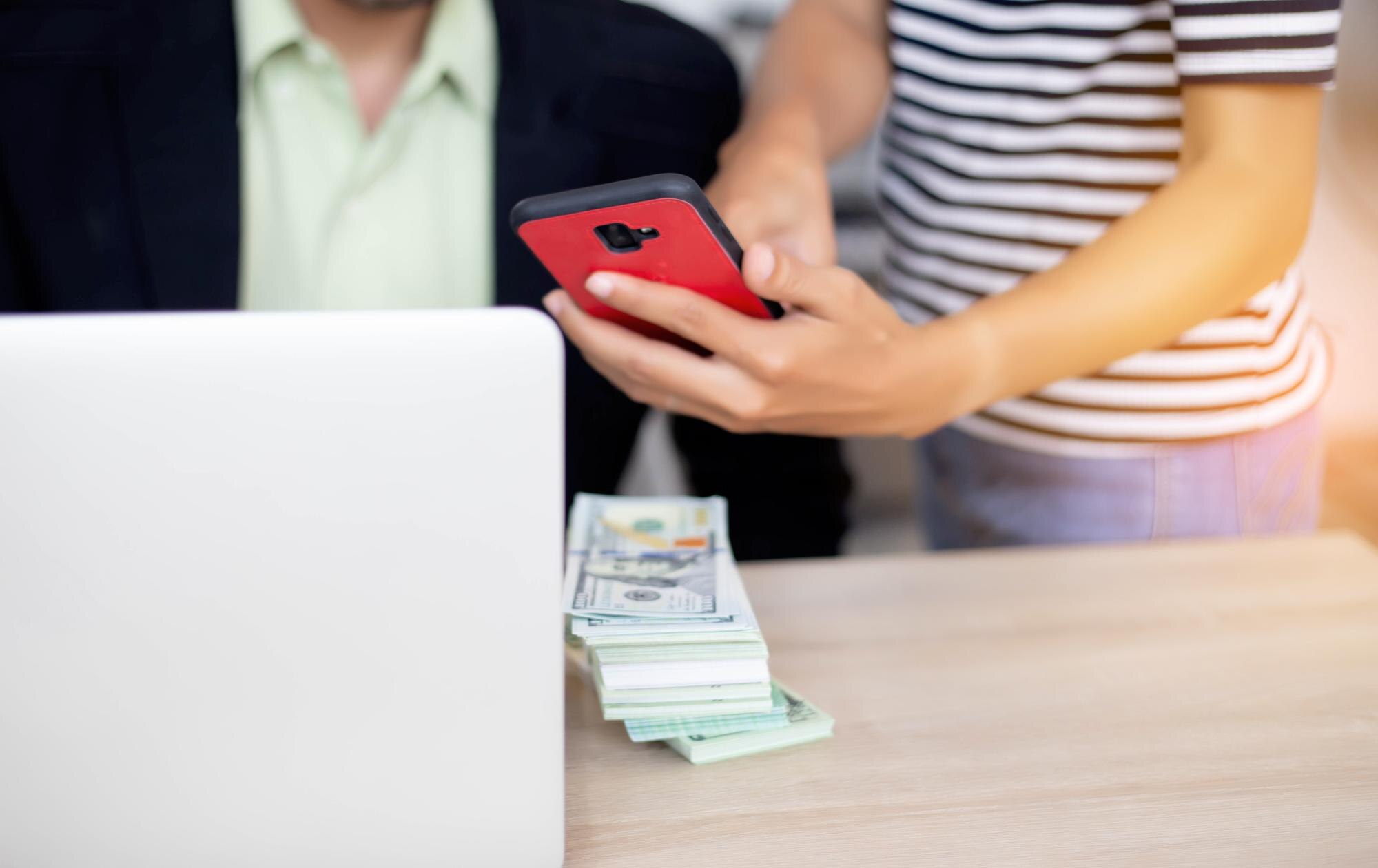 Środkowa sekcja kobiety pokazującej smartfon biznesmenowi za pomocą laptopa