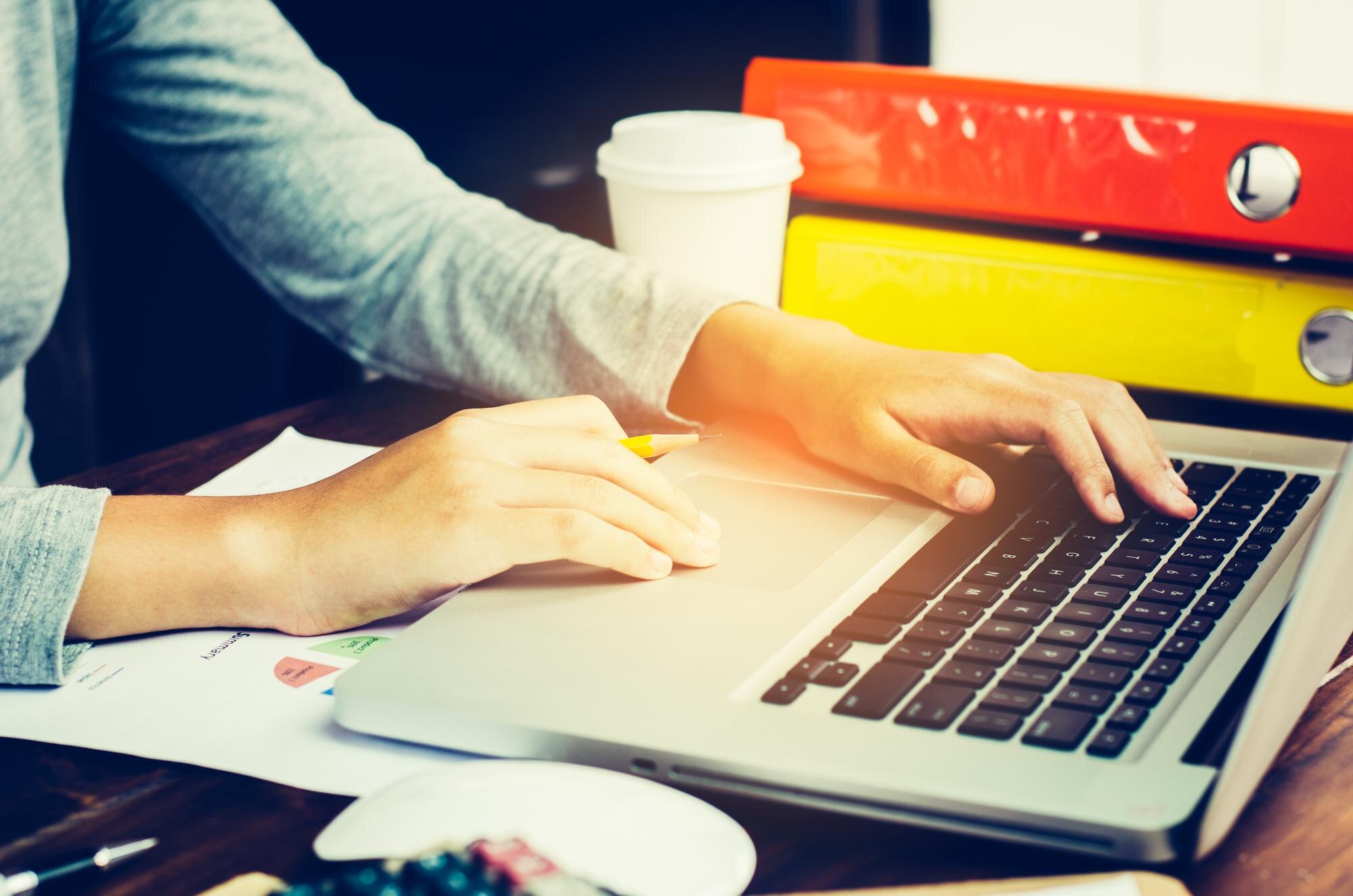 Przycięte ręce bizneswoman używającej laptopa przy biurku