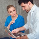 Lekarze dyskutują przez laptop przeciwko ścianie w szpitalu