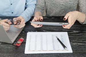 Środkowa sekcja kolegów używających cyfrowego tabletu za pomocą laptopa i raportu na biurku