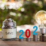 Oszczędność pieniędzy i monet w szklanej butelce na drewnianej podłodze. Koncepcja inwestycji na przyszłość. Z tłem bokeh