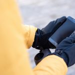 Mężczyzna dostawy żywności na skuterze za pomocą swojego smartfona. Żółta kurtka i czarne rękawiczki. Zimowy