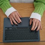 Nieuznawalna kobieta pracująca na laptopie w domu, bliskie ręce kobiety piszące na komputerze.