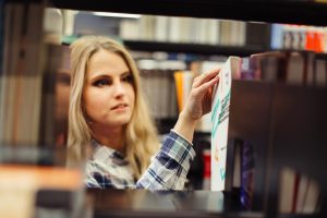 Dziewczyna zbieranie książek w bibliotece