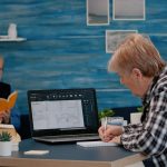 Starszy architekt analizujący cyfrowy prototyp z planami z laptopa