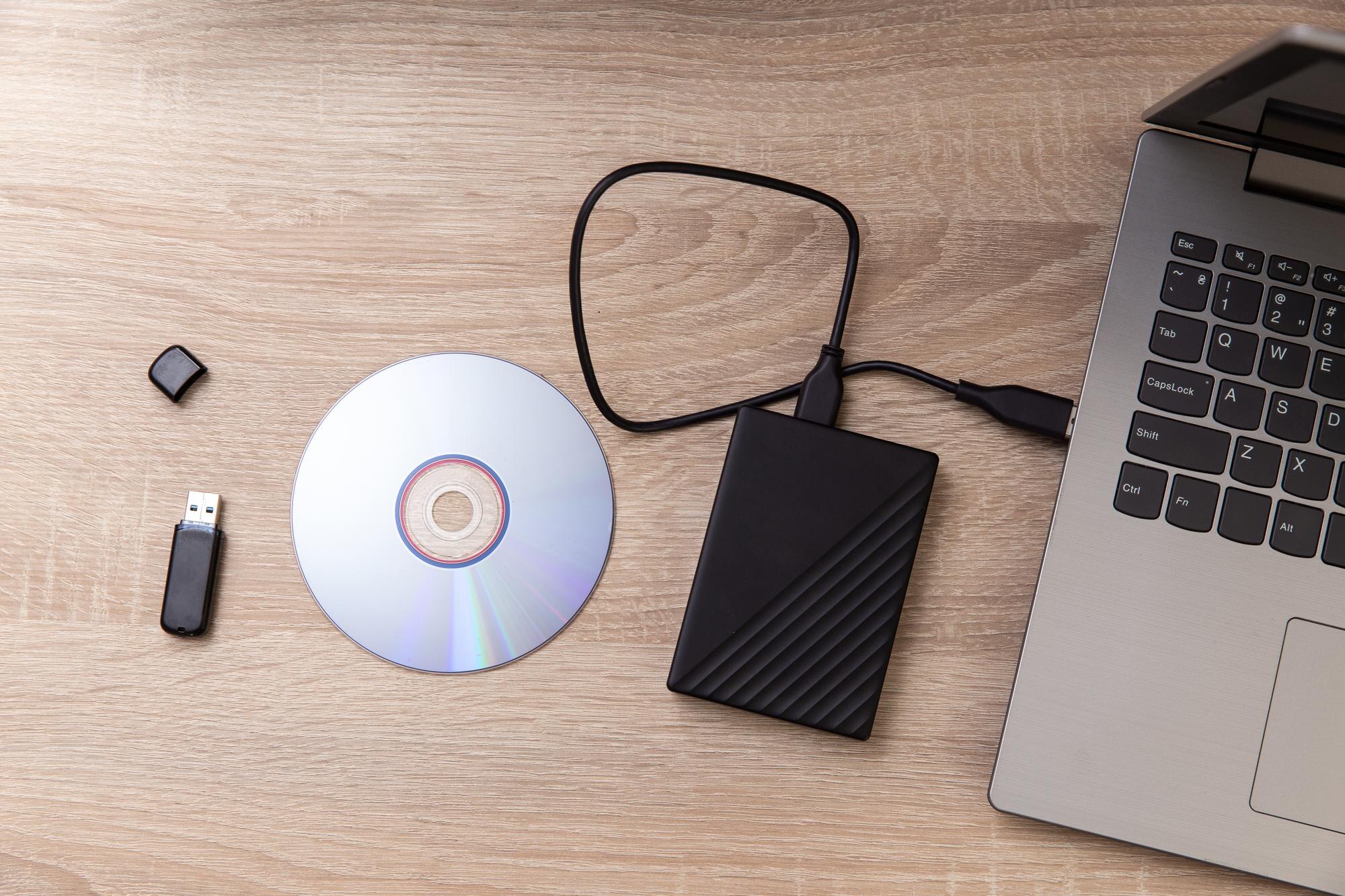 Cyfrowi opiekunowie informacji Zewnętrzny twardy dysk CD i pamięć flash USB laptop na drewnianym stole