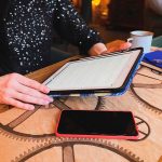 Zbliżenie dziewczyna pracuje lub studiuje w kawiarni z tabletem, telefonem i notebookiem są w pobliżu. Coworking, organizacja pracy. Koncepcja biznesu lub edukacji.