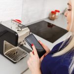 dziewczyna siedzi na kanapie i trzyma telefon z programem smart home na ekranie