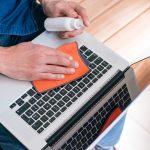 Widok z góry. młody mężczyzna leczący laptopa przed bakteriami koronawirusa