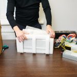 Mężczyzna rozpakowuje pudełko sprzętu do kopania kryptowaluty bitcoin