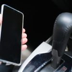 Ręka osoby trzymającej telefon komórkowy w samochodzie