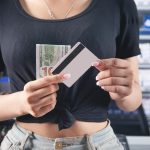 Kobieta trzyma kartę kredytową i pieniądze w supermarkecie.