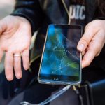 Telefon z pękniętym ekranem w dłoni sprawa nieobjęta gwarancją