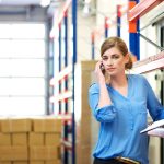 Żeński logistyka pracownik na telefonie komórkowym w magazynie