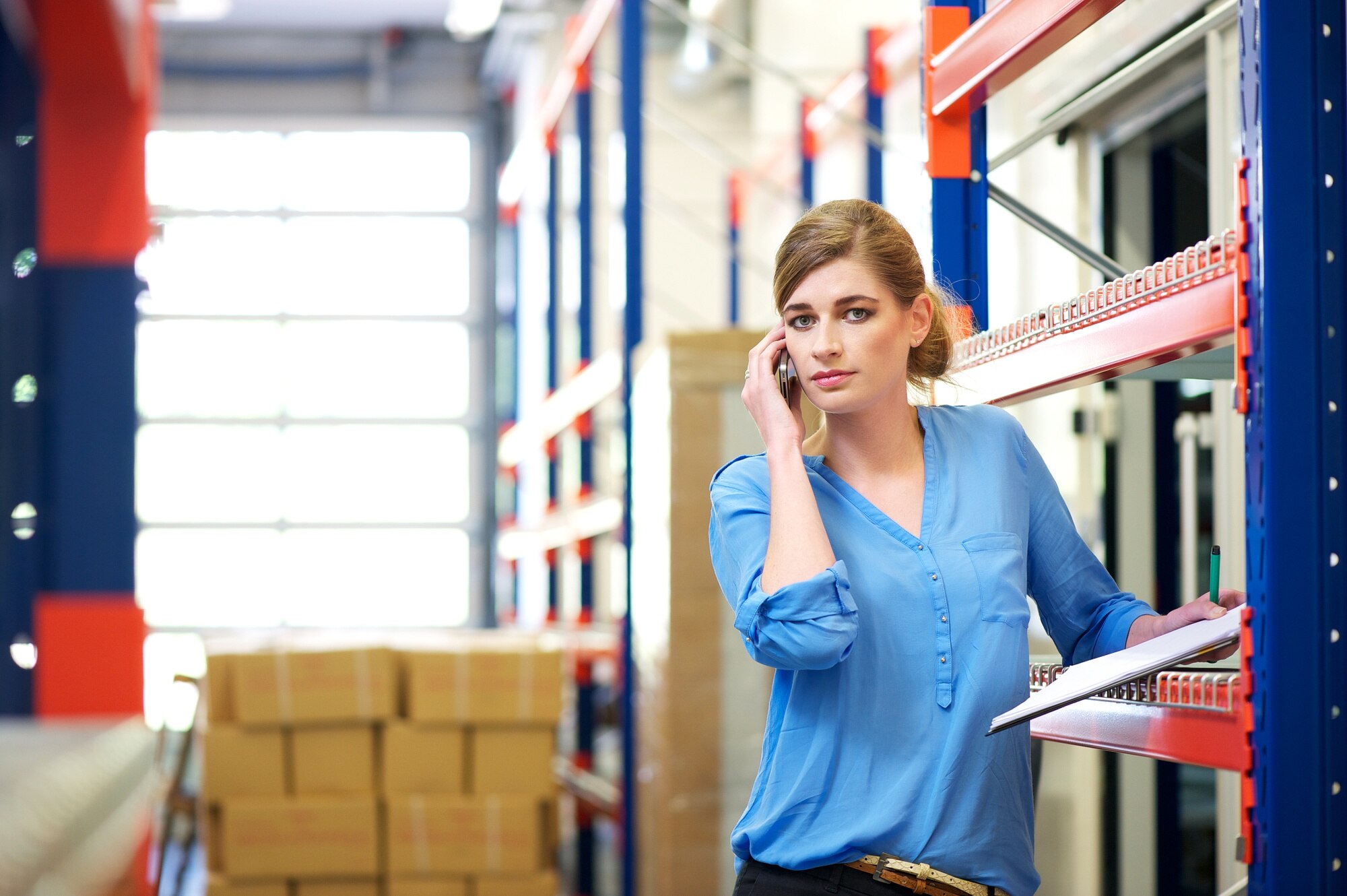 Żeński logistyka pracownik na telefonie komórkowym w magazynie