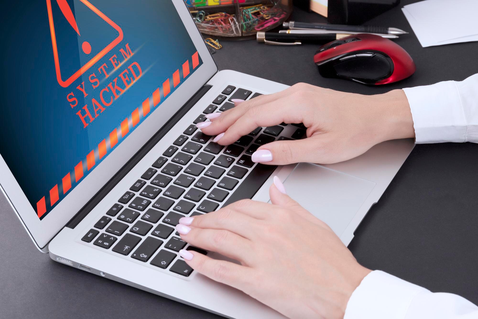 Kobiece dłonie z manicure na klawiaturze laptopa i ostrzeżeniem na ekranie komputera zhakowane Zdjęcie wysokiej jakości