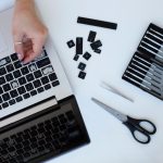 Młoda kobieta czyści klawiaturę laptopa