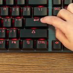 dziecko naciśnie palcem na czarnej klawiaturze z czerwonym podświetleniem