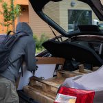 Mężczyzna załadowujący pudełka do bagażnika samochodu