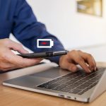 Biznesmen trzymający telefon z ekranem niskiego poziomu naładowania baterii