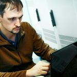 Portret programisty przy pracy Autentyczna scena Informatyk pracuje na laptopie w serwerowni