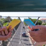 Kilka osób trzyma telefon komórkowy w pokrowcach dopasowanych do ubrania Stojąc na moście nad ruchem miejskim