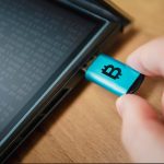 Hardwarowy portfel dla kryptowaluty podłączony do laptopa w ręku człowieka zimny sposób przechowywania kryptowalut na przenośnym nośniku jest sposobem ochrony oszczędności Bezpieczny offline portfel Bitcoin na dysku flash