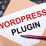 Biała kartka z napisem WORDPRESS PLUGIN w rzemieślniczej kopercie na biurku z nowoczesną klawiaturą laptopa i bordowym długopisem Płaski układ miejsca pracy