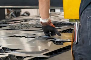 Wycinarka laserowa tnie arkusze drewna, podczas gdy mężczyzna zajmuje się procesem ameryka łacińska