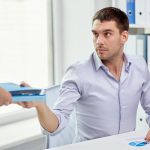 koncepcja biznesu, ludzi i papierkowej roboty - biznesmen biorący folder z dokumentami od sekretarki w biurze