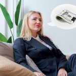 Atrakcyjna kobieta w szarym garniturze siedzi na kanapie Kobieta myśli o wynagrodzeniu pieniężnym lub wygranej na loterii