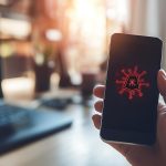 ktoś trzymający telefon komórkowy z czerwonym znakiem korony