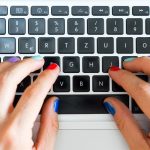 Biuro domowe lub zakupy online Palce kobiety z kolorowymi paznokciami piszą na klawiaturze notebooka