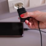 Kobieta z ładowarką do telefonu komórkowego w nasadce na ścianie