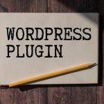 Notatnik z tekstem WORDPRESS PLUGIN długopis i okulary leżą na drewnianym biurowym stole