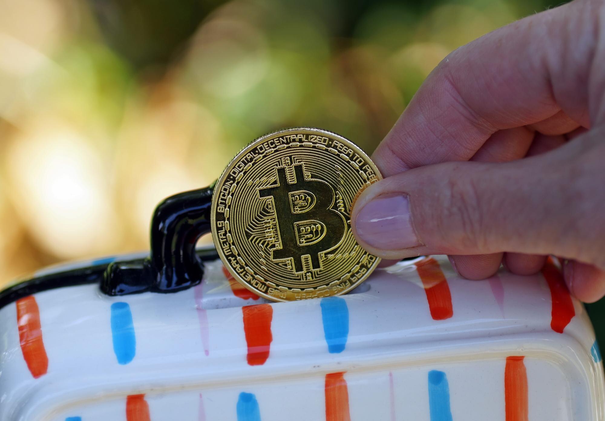 Zbliżenie dłoni trzymającej żółtą monetę ze znakiem bitcoin