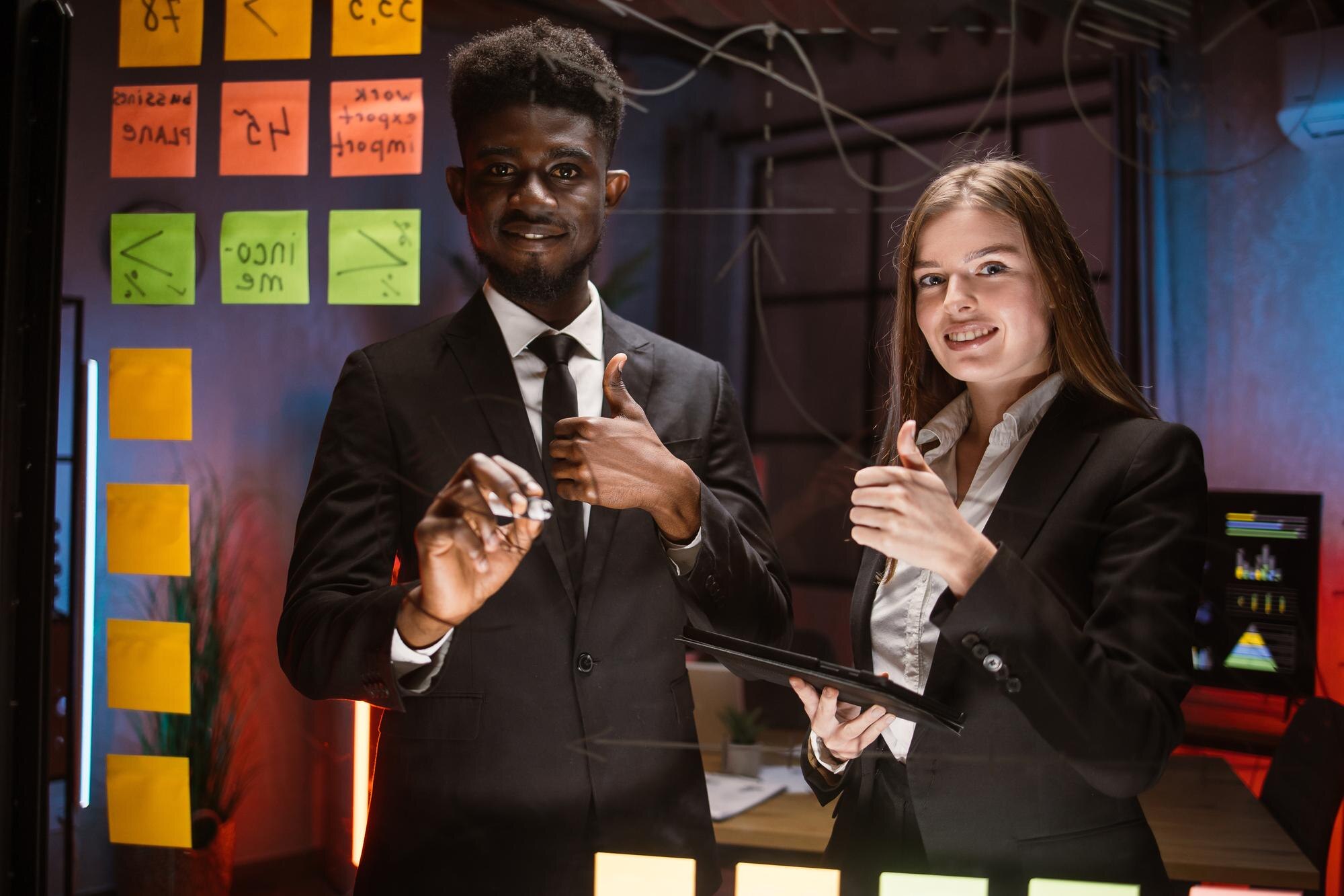 Ludzie w strojach formalnych, używający samoprzylepnych notatek i piszący, stojąc za szklaną ścianą