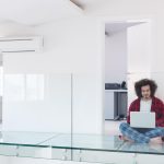 młody freelancer w szlafroku pracujący w domu za pomocą laptopa, siedząc na podłodze