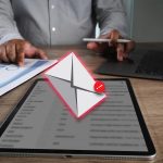 Phishing mail person working desk with tablet displaying email notification laptop and documents with charts indicating business or office