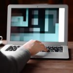 Womans hands typing on laptop at the table over blurred background