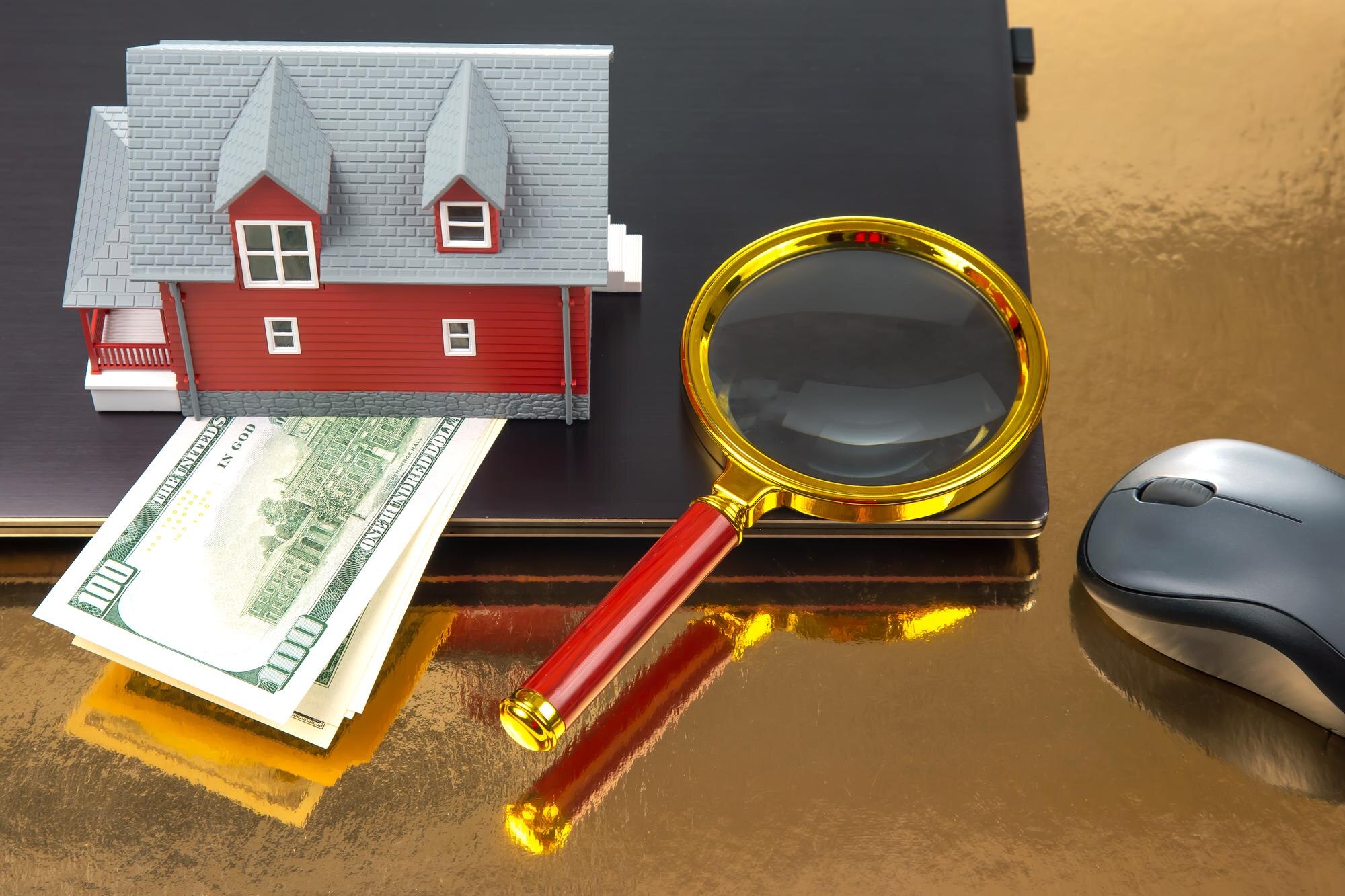 Znalezienie i zakup domu przez Internet Model domu na tle laptopa i lupy