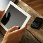 Ręce trzymające cyfrowy tablet na drewnianym tle stołu