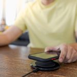 Ładowanie baterii telefonu komórkowego za pomocą urządzenia bezprzewodowego w stole Ładowanie smartfonu na poduszce ładującej Telefon komórkowy w pobliżu ładowarki bezprzewodowej