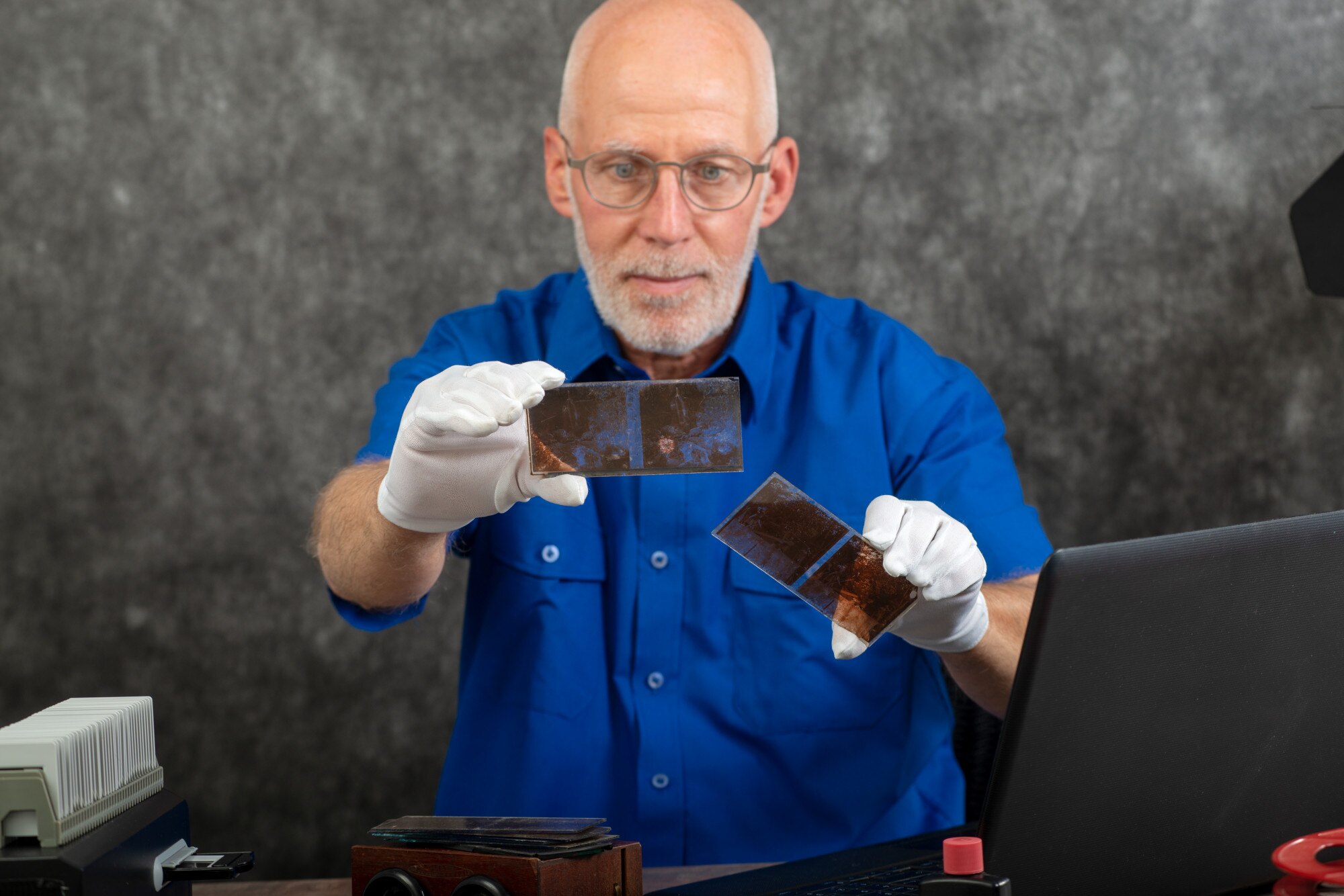 Technik w białych rękawiczkach digitalizuje starą fotografię na szklanym talerzu