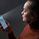 Kobieta skanuje twarz za pomocą systemu rozpoznawania twarzy na telefonie komórkowym w celu identyfikacji biometrycznej. Przyszłościowa technologia i identyfikator twarzy