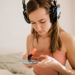 Kobieta trzyma smartphone i markiera z hełmofonami