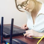 Kobieta łączy Internetowego kabel włącznik na laptopie