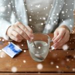 Opieka zdrowotna, medycyna i ludzie Koncepcja bliska chorej kobiety mieszającej leki w filiżance z łyżką nad śniegiem